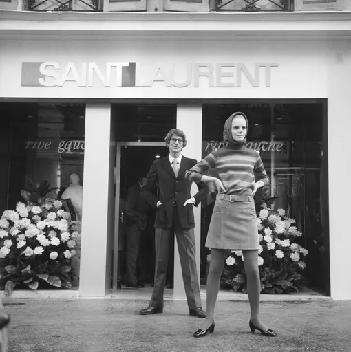 Ив Сен-Лоран и шведская модель Улла Каремби перед первым бутиком Saint Laurent Rive Gauche, 1966 Ив Сен-Лоран и шведская модель Улла Каремби перед первым бутиком Saint Laurent Rive Gauche, 1966