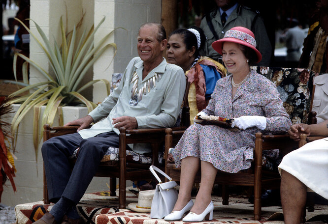 Королева Елизавета II и принц Филипп в традиционном ожерелье из ракушек, наблюдают за танцорами 27 октября 1982 года в Тувалу